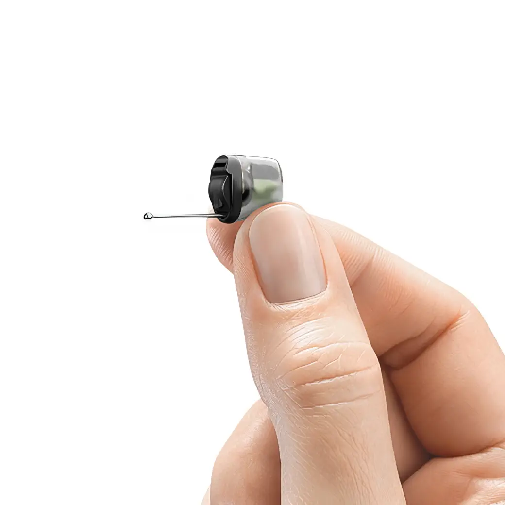 A hand holds a small, discreet hearing aid with a thin wire and tip, suggesting usage for improved hearing.